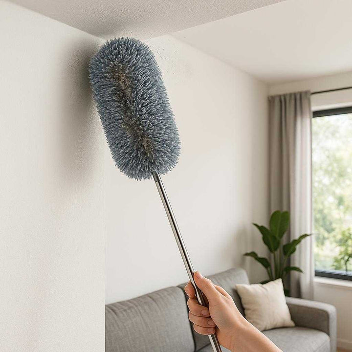 Avanceret Fleksibel Støvfjerner med Mikrofiberhoved og Teleskopskaft til Effektiv Rengøring. The advanced flexible duster with a microfiber head is being used to clean a high, hard-to-reach ceiling corner in a modern living room, with dust visibly captured on its fibers.