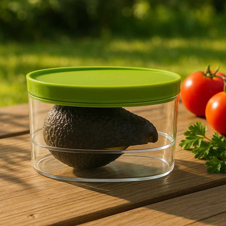 Avocadobeholder i moderne design - Bevar friskheden af dine halve avocadoer: A different realistic picnic setting where the product is securely positioned on a wooden picnic table, naturally placed amongst other fresh ingredients like tomatoes and herbs.