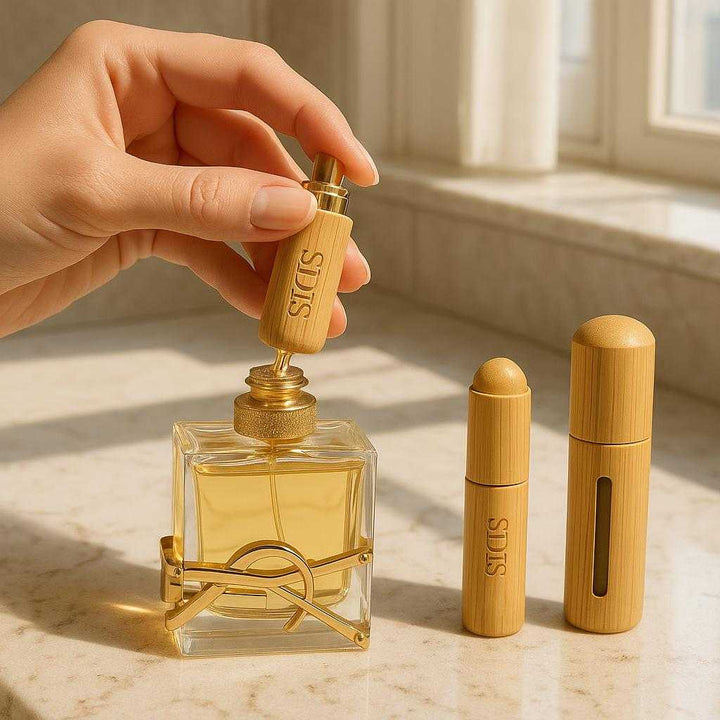 Bambus Skal Parfume Forstøver - 5ml & 8ml Direkte Genopfyldning/Opladning: A realistic vanity setting where the Bambus Skal Parfume Forstøver is properly grounded on a marble bathroom counter, being actively refilled from a large perfume bottle by a hand.