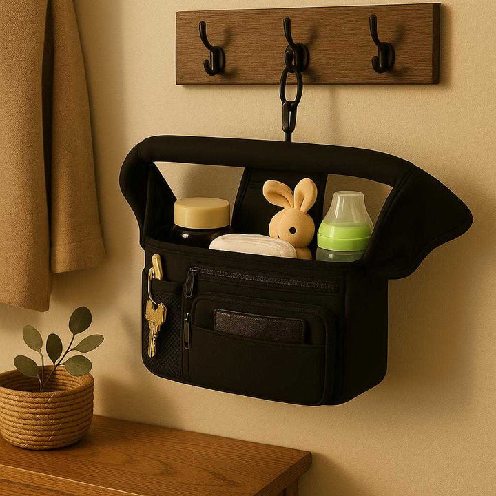 Barnevogns Manager i Stof, Net og Plastik - Sort, Lyserød, Lyseblå, Lys Grå - God Kvalitet: A different realistic home entryway setting where the product is securely positioned on a wall-mounted hook, being naturally placed to organize small items like keys and a wallet, with proper physics and realistic integration into the tidy and welcoming environment, and warm indoor lighting casting soft shadows on the wall.