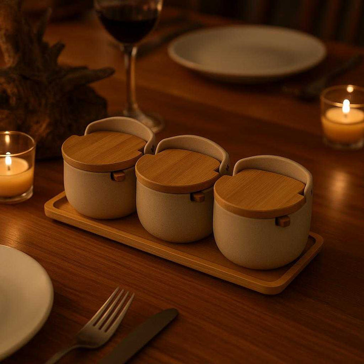 Beholdere til Krydderier - Moderne Sæt med 3 Keramiske Beholdere og Bambuslåg - Beige og Lys Brun. The modern set of three ceramic spice holders is beautifully displayed on a dining table, complemented by a rustic wooden centerpiece and ambient candlelight during a cozy dinner gathering.