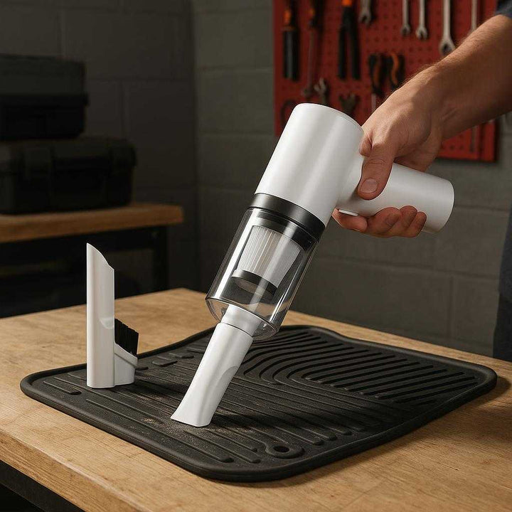 Bilstøvsuger Ledningsfri - Kompakt og Effektiv til Bilrengøring, Høj Kvalitet: A different realistic home garage setting where the product is securely positioned on a sturdy workbench, being used to clean dust from a car floor mat, with proper physics, shadows, and realistic integration into the environment.