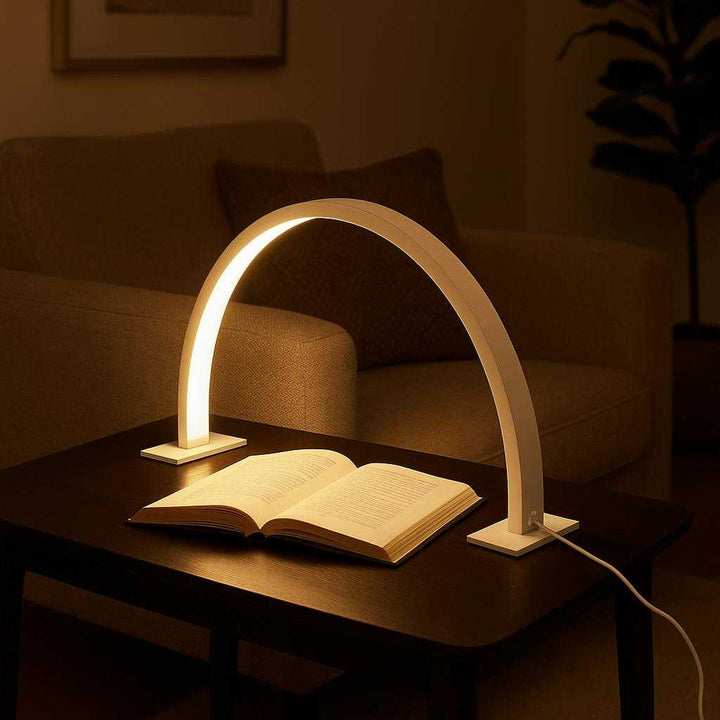 Bordlampe uden ledning – Moon Light LED-lampe med touch, Hvid og Lyserød: A realistic modern living room setting where the Moon Light LED-lampe is properly grounded on a sleek side table beside a cozy armchair, being naturally placed and slightly angled as if subtly illuminating a late-night book reading session.