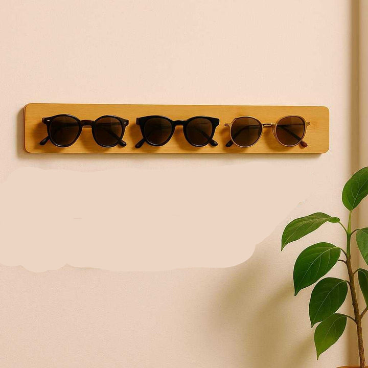 Brilleholder i Bambus – Elegant og Funktionel Opbevaring til Bilen og Hjemmet. The bamboo holder is fixed on a hallway wall at home, neatly organizing various sunglasses with a potted plant nearby for a touch of nature.