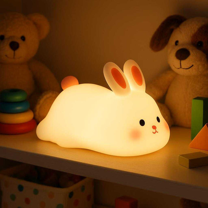 Børnelampe Kanin – Blød Silikone Natlampe med LED og Touch til Børneværelse: A different realistic setting in a cozy playroom where the Børnelampe Kanin is securely positioned on a low shelf amid soft toys and playthings.