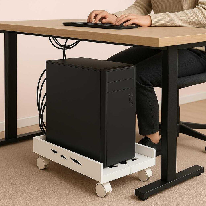 Computerholder på Hjul i Hvid og Sort - Elegant og Praktisk Design til Kontoret. The elegant and practical white and black computer holder on wheels supports a sleek desktop CPU beneath a modern office desk, with cables neatly arranged and a person working on the computer above.
