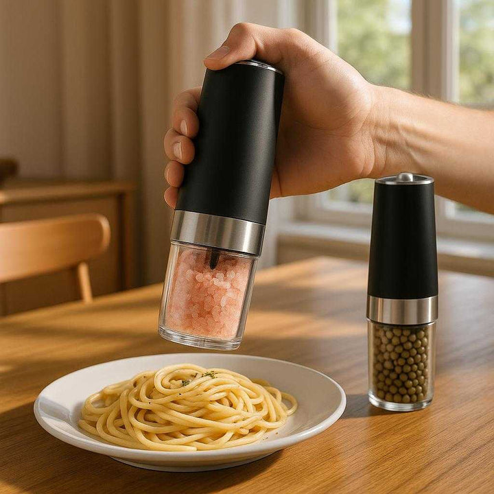 Design Elektrisk Salt og Peber Kværn - Sort/Sølv, Holdbart Metal og Plastik: A realistic modern kitchen setting where the electric salt and pepper grinder is properly grounded on a polished wooden dining table, being actively used by a hand to season a freshly cooked pasta dish.