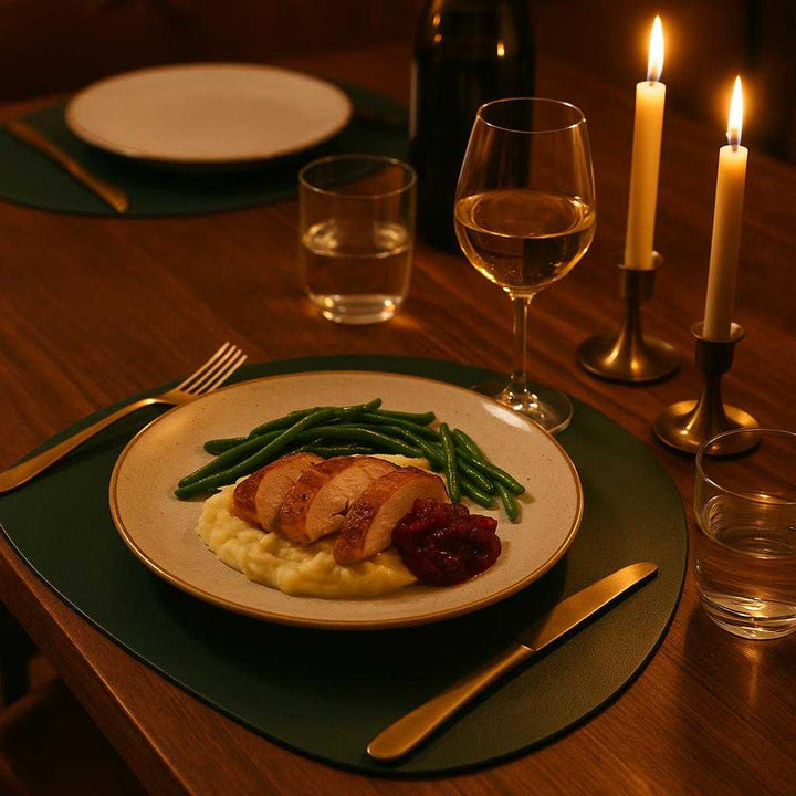 Dækkeserviet i mørkegrønt PU-læder - Sæt med 8 stk. i moderne design. The mørkegrøn dækkeserviet is beautifully set on an elegant dining table beneath ambient candlelight, with exquisite dinnerware and a deliciously plated meal creating a warm, inviting atmosphere for a family gathering.