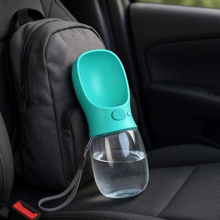 Drikkedunk til Hunde - Praktisk og Holdbar Løsning i Turkis Design med Gennemsigtig Flaske og Skålformet Top: A different realistic car setting where the product is securely positioned on the seat beside a backpack, naturally placed for easy access during a road trip.