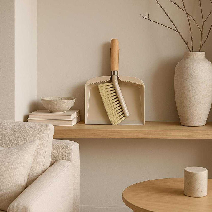 Fejebakke og kost i moderne design - Kompakt og nem at opbevare, i beige og træ. Displayed in an elegantly minimalistic living room, the compact dustpan and brush sit neatly on a shelf, surrounded by stylish decor, showcasing its easy storage and contemporary aesthetic.