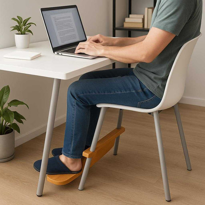 Fodstøtte i Bambus - Stilfuld Ergonomisk Komfort til Kontor og Hjemmet. The bamboo footrest is securely attached to a modern desk chair in a sleek home office, providing ergonomic support as a person works on a laptop.