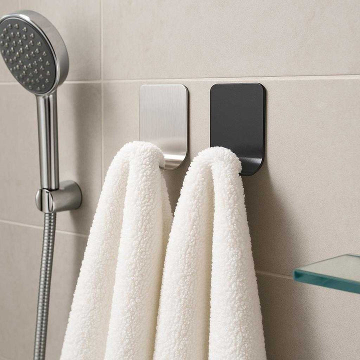 Funktionalitet i Elegante Sølv og Sort Krogdesign - Moderne Badeværelsesopbevaring: A realistic modern bathroom setting where the product is properly grounded on a smooth tiled wall, being naturally placed to hold a fluffy white towel.