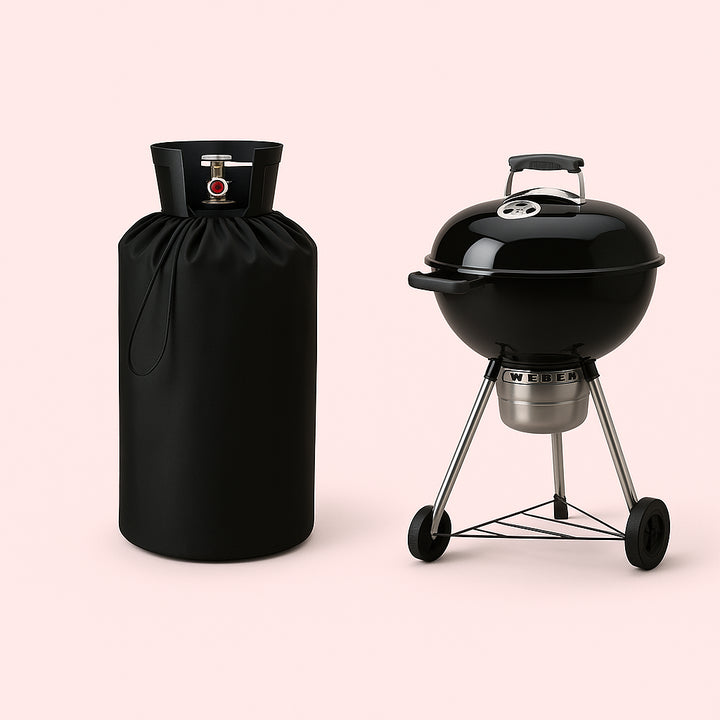 Enhanced Gasflaskebetræk i Robust Plast med Tappehane - Praktisk og Elegant Beskyttelse til Din Gasflaske. The gas bottle cover in robust black plastic is protecting a gas cylinder on a vibrant patio, with a barbecue grill nearby and friends gathering for a cookout under string lights.