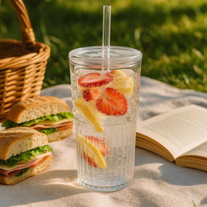 Glaskop med låg og sugerør - Praktisk og funktionel til kolde drikke: A different realistic outdoor picnic setting where the glass tumbler is securely positioned on a picnic blanket.