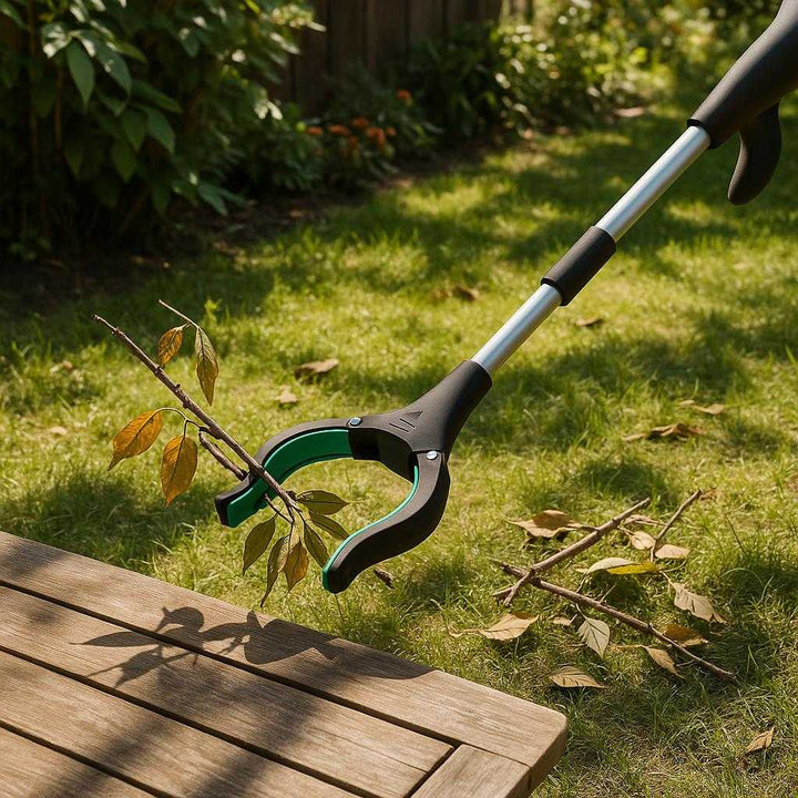 Gribe værktøj i plastik, aluminium og gummi - Blå, Orange, Grøn - Ergonomisk og let at bruge: A different realistic outdoor garden setting where the grabber tool is securely positioned on a wooden garden table, being used naturally to pick up fallen branches and leaves from the grass, with proper physics, shadows casting across the grass, and realistic integration into the garden environment with nearby plants and sunlight filtering through the trees.