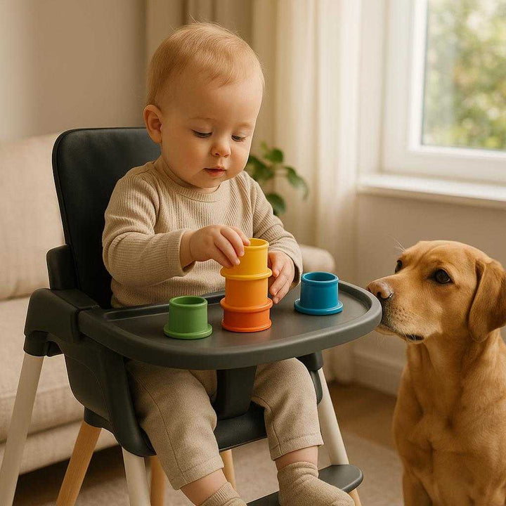Højstolsbakke i Moderne Design - Praktisk og Stilfuld Spisebakke til Baby Højstol i Sort, Hvid og Grå: A different realistic living room environment where the product is securely positioned on a modern highchair, naturally placed with a toddler sitting and playing with stacking toys on the tray.