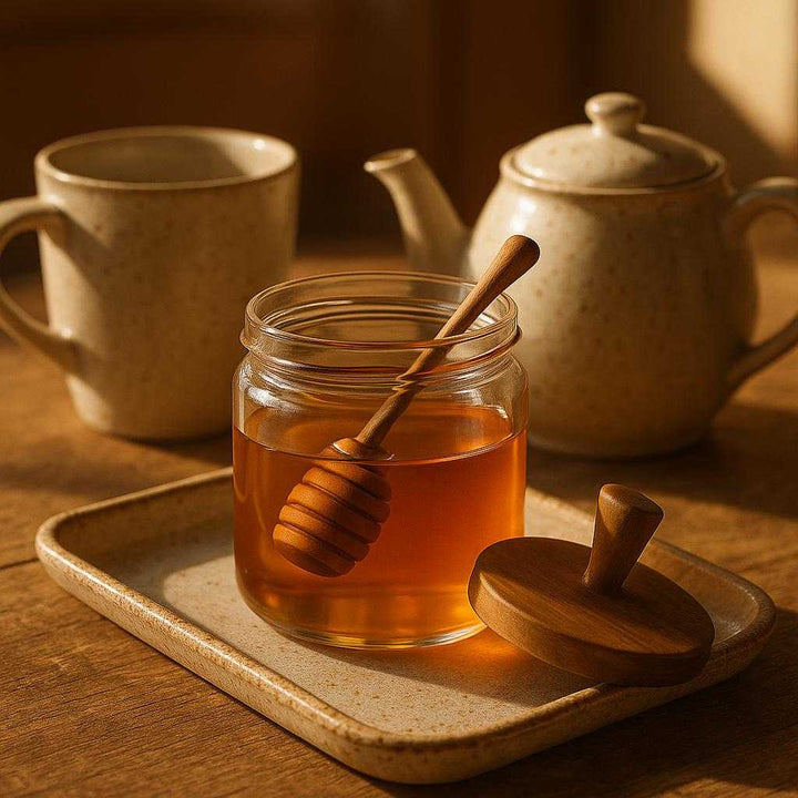 Honning krukke i glas, træ og metal - let at bruge, æstetisk, multifunktionel - 1pc'er (500ml): A different realistic breakfast table setting where the honey jar is securely positioned on a rustic ceramic tray alongside a teapot and a mug.