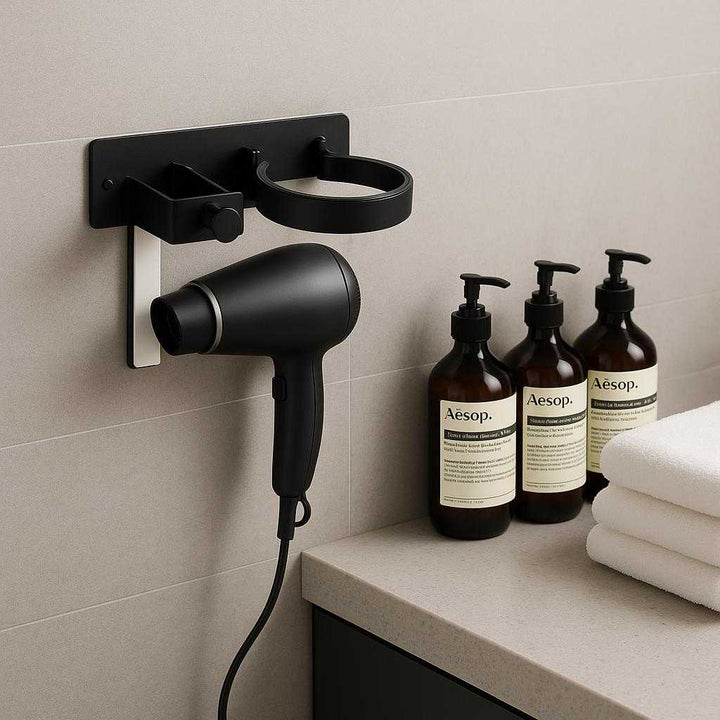 Hårtørrerholder til Væg – Avanceret Metal Design med Sort Finish for Moderne Badeværelse. The stylish black wall-mounted hair dryer holder is seamlessly integrated into a minimalist bathroom setup, next to a set of premium toiletries and plush white towels, highlighting the chic and organized atmosphere.