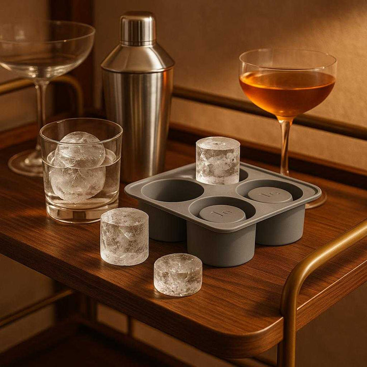 Isterningsbakke i moderne design - Skaber store, cylinderformede isterninger med nem frigivelse: An elegant home bar environment where the ice cube tray is securely positioned on a wooden bar cart, surrounded by cocktail glasses and a cocktail shaker.