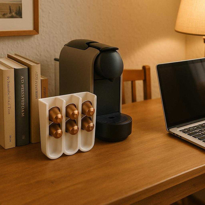 Kaffekapselholder med plads til 20 kapsler - Moderne design i hvid plast. Set in a cozy home office, the coffee capsule holder is conveniently placed next to a coffee maker on a wooden desk, amidst books and a laptop, highlighting a perfect work-from-home setup.