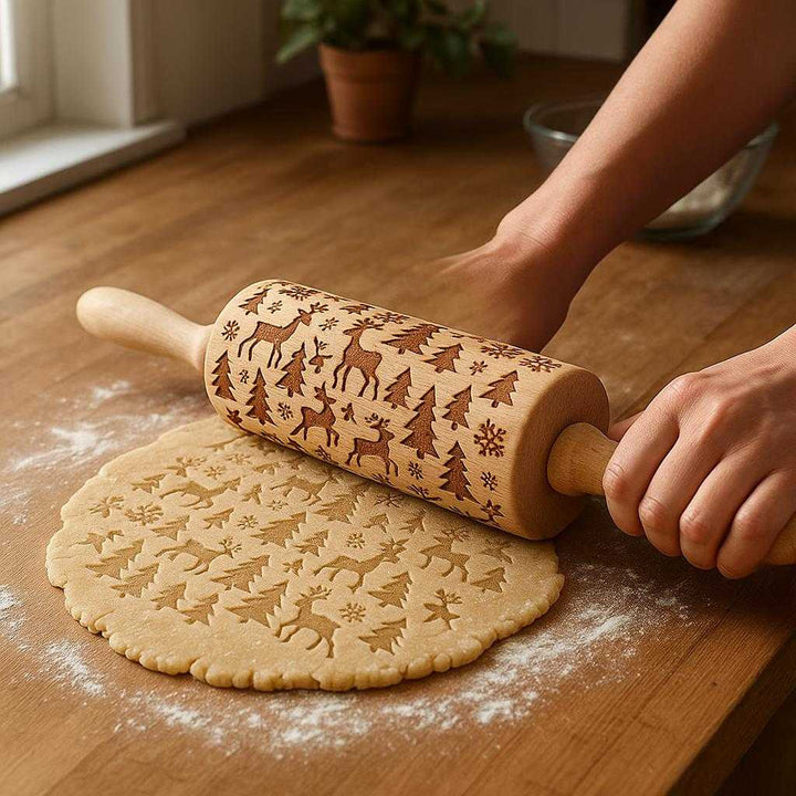 Kagerulle med Julemønster i Træ til Småkager - Høj Kvalitet med Mønstrede Varianter: A realistic kitchen setting where the rolling pin with Christmas pattern is properly grounded on a wooden countertop, being actively used by a person's hands to roll out cookie dough.