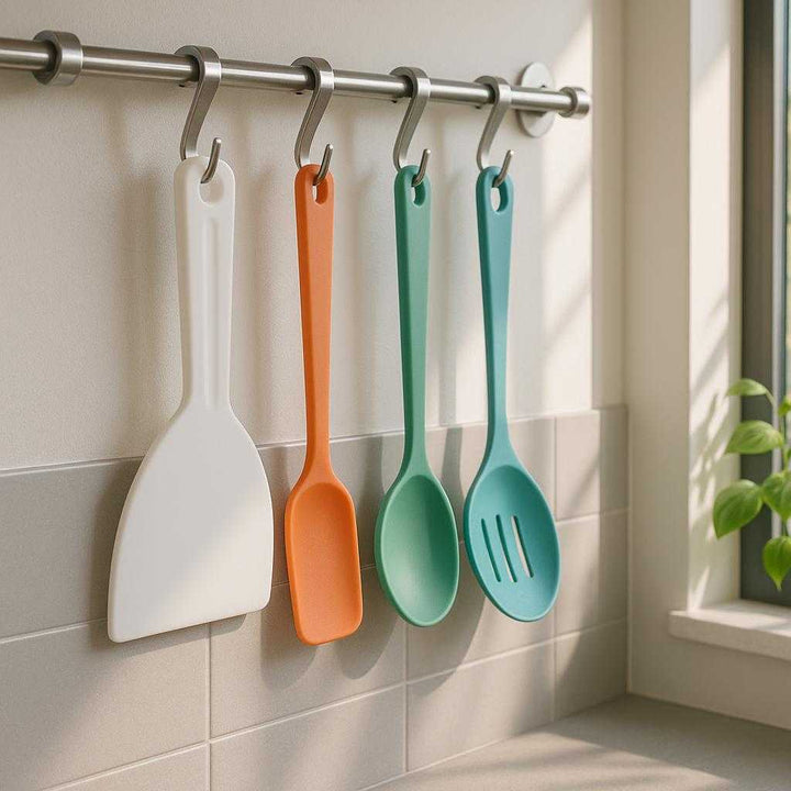 Kageskraber i høj kvalitet - Moderne design, let at rengøre, holdbar plastik, hvid farve. A pristine white scraper hangs on a kitchen hook rack beside colorful utensils, complementing the sleek, minimalist kitchen décor with sunlight streaming through a nearby window.