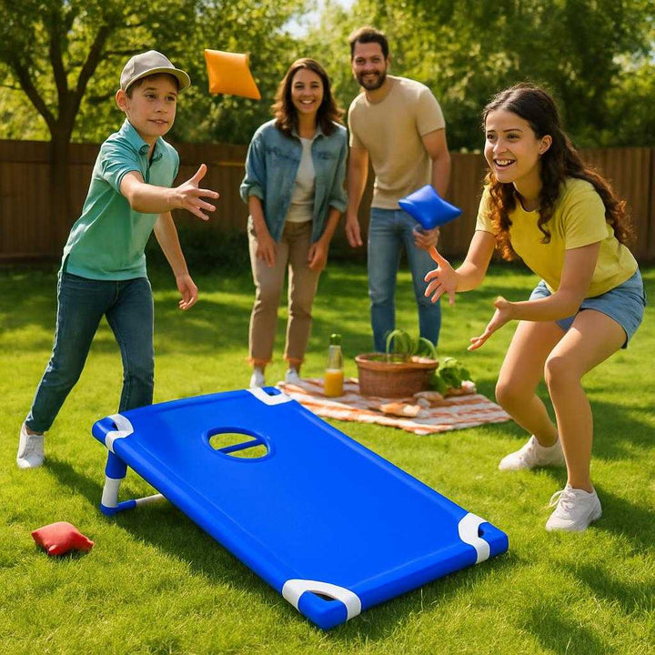 Kaste Spil i Slidstærk Polyester og Robust Plast - Perfekt til Indendørs og Udendørs Brug. The blue cornhole board set up on grass in a backyard, with players tossing bean bags in a lively family picnic setting on a sunny day.