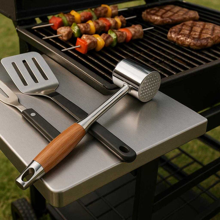 Kødhammer i Rustfrit Stål og Træ - Forbedrer Kødets Tekstur, 1 stk: A different realistic barbecue setup where the meat tenderizer is securely positioned on a metal grill side table, placed naturally next to grilling tools.