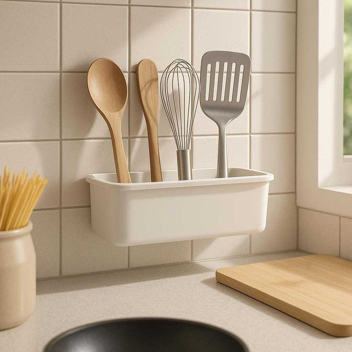 Køkken opbevaringsmodul i hvid plast - Væghængt design med skjult montering: A realistic modern kitchen setting where the product is properly grounded on a tiled kitchen backsplash, being naturally placed above a countertop, used for storing various cooking utensils in an organized manner, with natural daylight streaming through a nearby window casting soft shadows and showing clear contact points where the product is mounted on the wall.