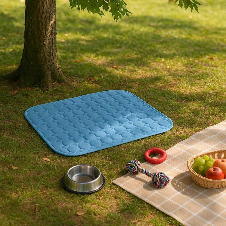 Kølemåtte til hund: Selvaktiverende, slidstærk og let at transportere - Tilgængelig i Blå, Lyserød, Grå og forskellige størrelser: A different realistic outdoor park setting where the Kølemåtte til hund is securely positioned on the grass, being naturally placed under a tree providing shade.