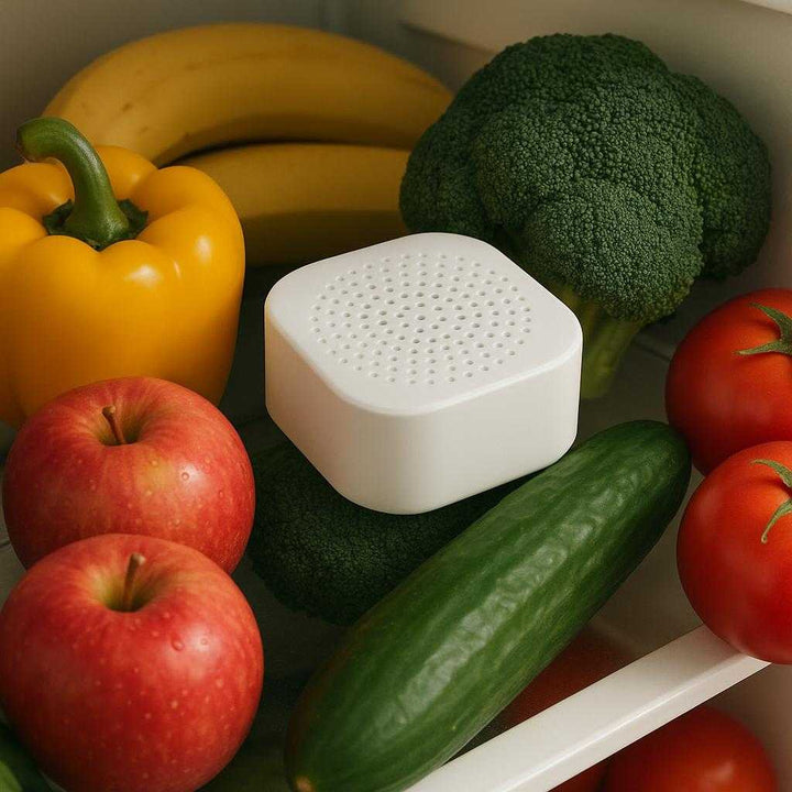 Køleskabsfrisker – Effektiv og Avanceret Lugtneutralisering med Høj Kvalitet. The Køleskabsfrisker is placed on a refrigerator shelf surrounded by fruits and vegetables, subtly absorbing odors while keeping the interior smelling fresh.
