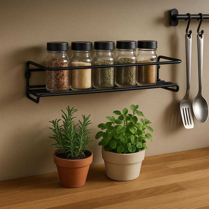 Krydderihylder i Sort Metal til Køkken - Små og Praktiske Vægmonterede Hylder: A different realistic kitchen setting where the spice rack is securely positioned above a wooden countertop, naturally placed with small potted herbs on it, adding a touch of green.
