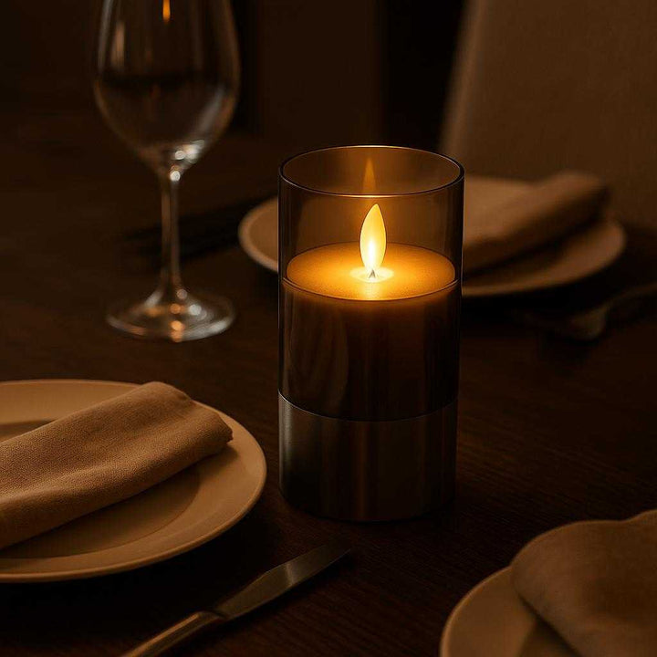 Ledlys med autentisk flammeeffekt - Moderne og minimalistisk design i sølv og grå. The LED candle with an authentic flame effect is set on a sleek dining table during a romantic dinner, casting a warm glow over elegant tableware and soft fabric napkins, creating an intimate and inviting atmosphere.