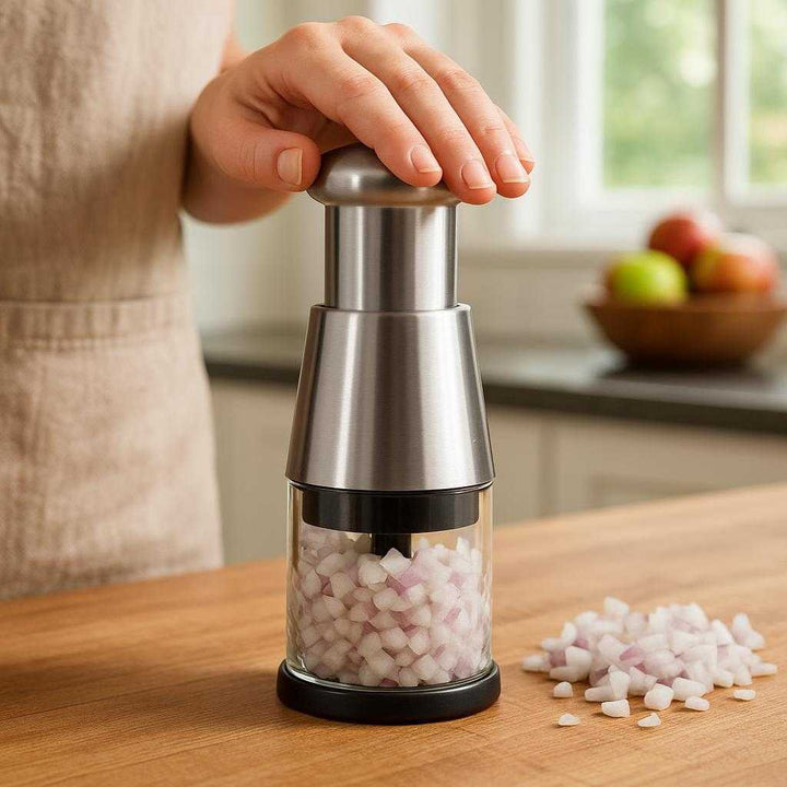 Løghakker med Effektiv Trykhakker og Beholder - Kompakt Design i Sort og Sølv: A realistic kitchen setting where the product is properly grounded on a wooden countertop, being actively used by a person to chop onions.