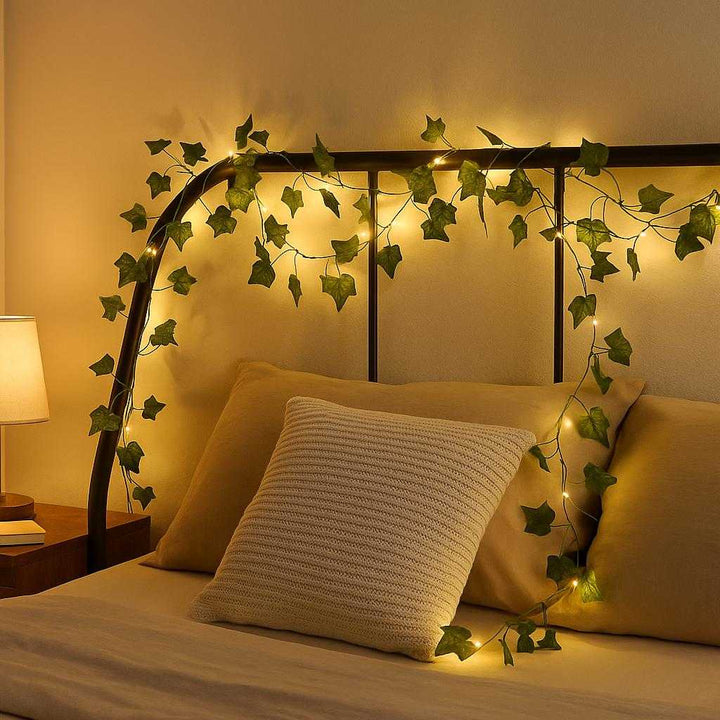Lyskæde med Kunstige Blade - Dekorativ Belysning til Indendørs Brug, Energibesparende LED, Grøn & Varm Hvid: A stylish bedroom environment where the light string is elegantly woven around a bed's headboard, illuminating the room with a soft, warm white light.