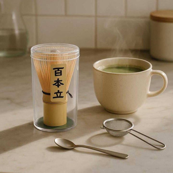 Matcha Piskeris i Bambus - Traditionelt Japansk Teudstyr til Perfekt Skummet Matcha: A different realistic modern kitchen setting where the Matcha Piskeris i Bambus is securely positioned next to a steaming cup of matcha on a marble countertop, naturally placed among other tea tools like a small sieve and a spoon, with soft morning light creating gentle shadows and blending seamlessly into the cozy environment.
