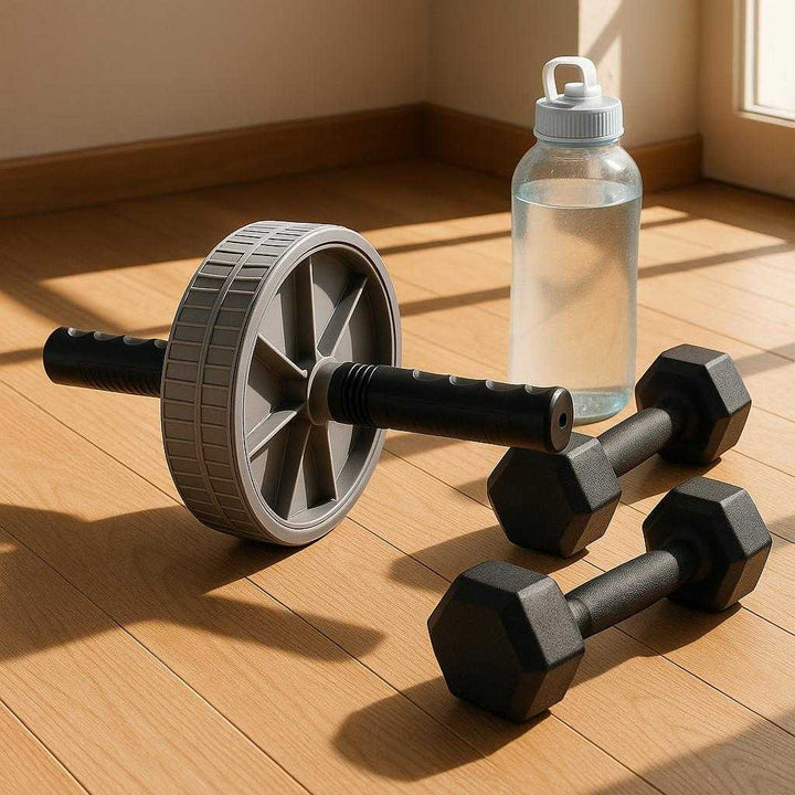 Mavehjul til Effektiv Core Træning – Høj Kvalitet, Med Elastik og Gråt Design. The versatile ab wheel is displayed neatly next to a set of dumbbells and a water bottle on a wooden floor, basking in natural sunlight filtering through a nearby window.