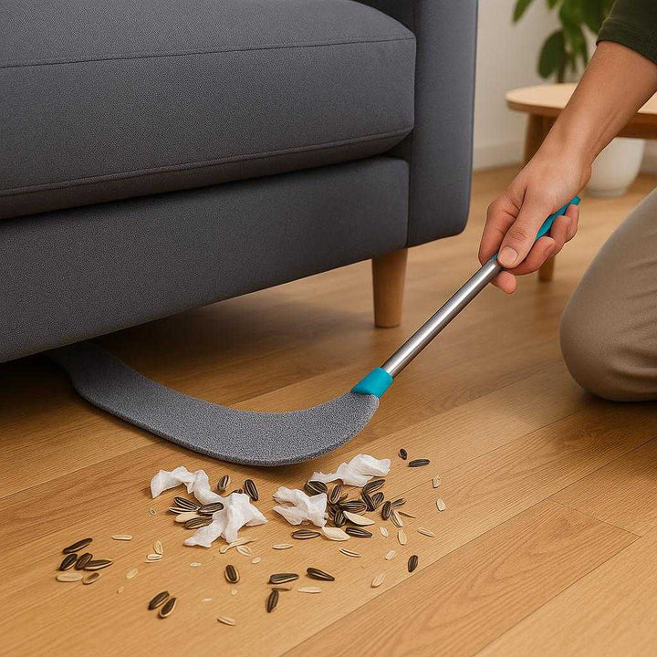 Mellemrum støvbørste i mikrofiber, plastik og metal - Støv Fjerkost - Fleksibel og effektiv: A realistic living room setting where the Mellemrum støvbørste is properly grounded on a wooden floor, being actively used by a person to clean underneath a sofa.