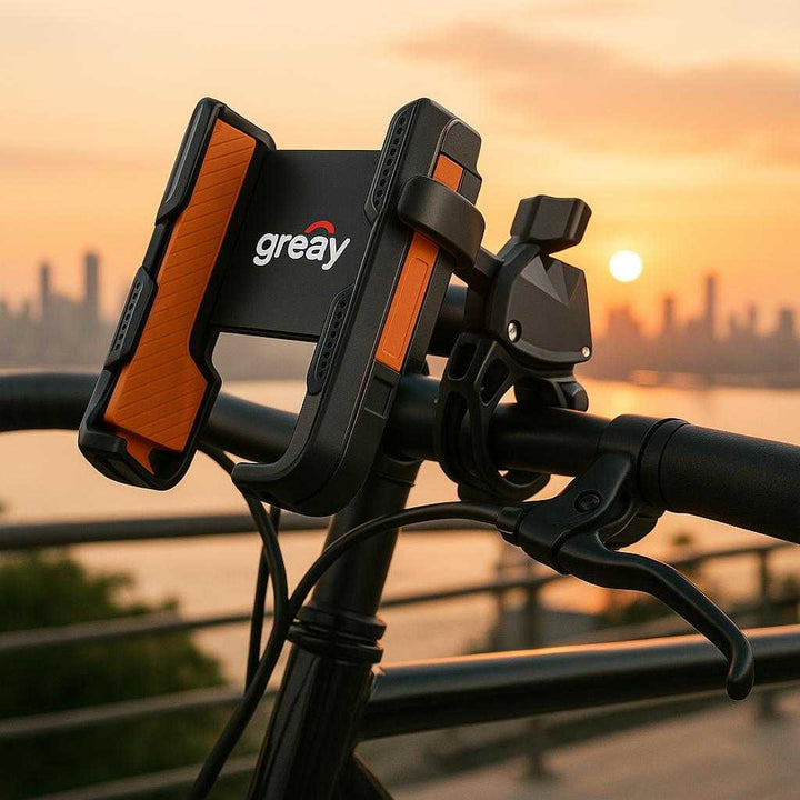 Mobilholder til Cykel - Justerbar og Stødabsorberende Sort Design med Orange Detaljer. A close-up of the stylish black and orange bike phone holder attached to the handlebars of a sleek city bicycle parked at a scenic urban viewpoint overlooking the sunset skyline.