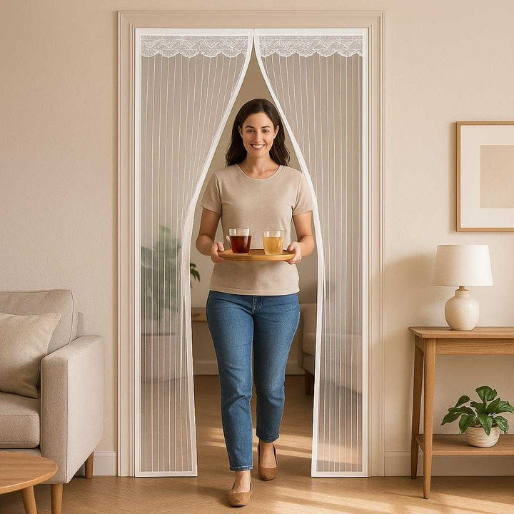 Myggenet - Magnetisk Skærmdør til Effektiv Insektbeskyttelse, Let og Praktisk: A realistic living room setting where the magnetically closing screen door is properly grounded on the doorway frame, being actively used by a person carrying a tray of drinks, showing the ease of hands-free entry with natural lighting casting realistic shadows on the floor and clear contact points where the door ties into the frame.