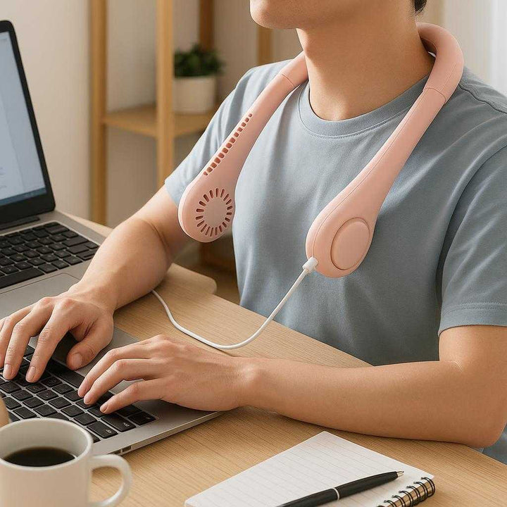 Nakkeventilator med 3 hastigheder, USB-genopladelig, lang batterilevetid - Tilgængelig i 5 farver: A realistic home office setting where the neck fan is properly grounded on a sleek, modern desk, being actively used by a person working on a laptop.