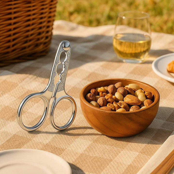 Nødde knækker i sølvfarvet rustfrit stål - Let at bruge, holdbar og ergonomisk: An outdoor picnic setting where the product is securely positioned on a picnic blanket, surrounded by a bowl of mixed nuts.