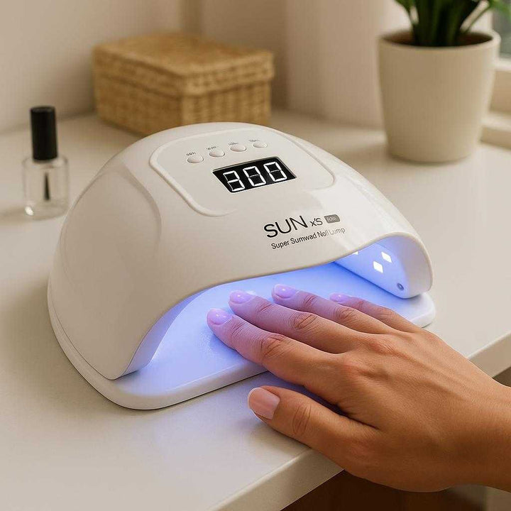 Negletørrer - Professionel og Effektiv UV/LED Tørring i Høj Kvalitet til Perfekte Resultater: A realistic home salon setting where the nail dryer is properly grounded on a sleek white countertop, actively used by a person's hands inserting neatly manicured fingers under the UV/LED lamp for drying, with natural lighting casting realistic shadows and showing clear contact points where the product touches the surface and fingers.