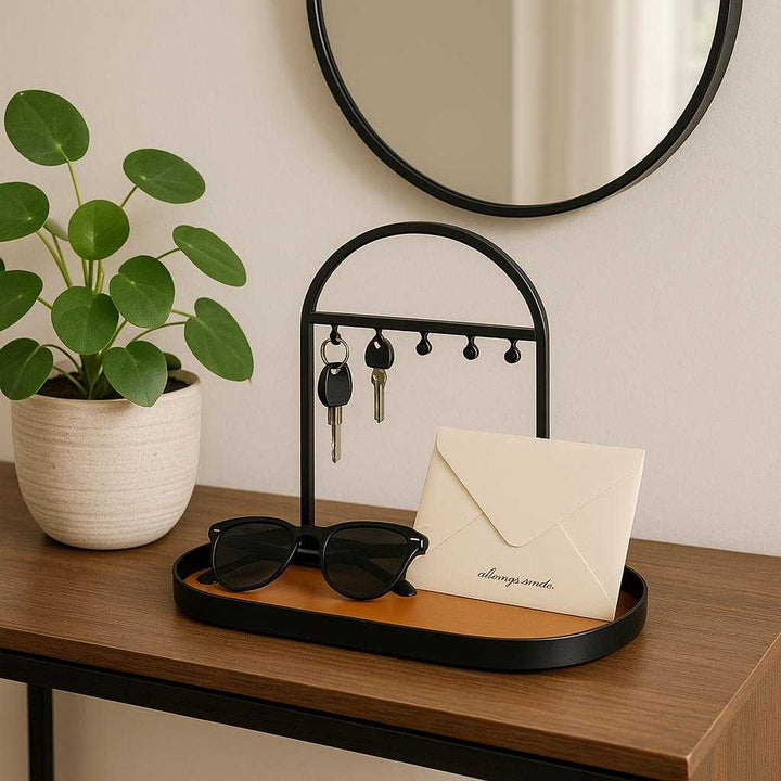 Nøgleholder med Bakke i Sort Metallisk Finish - Elegant Organizer til Entré eller Kontor, Moderne Design. Placed on a chic entryway console table, the black metallic key holder with tray holds sunglasses and mail, complemented by a decorative plant and a wall mirror reflecting soft daylight.