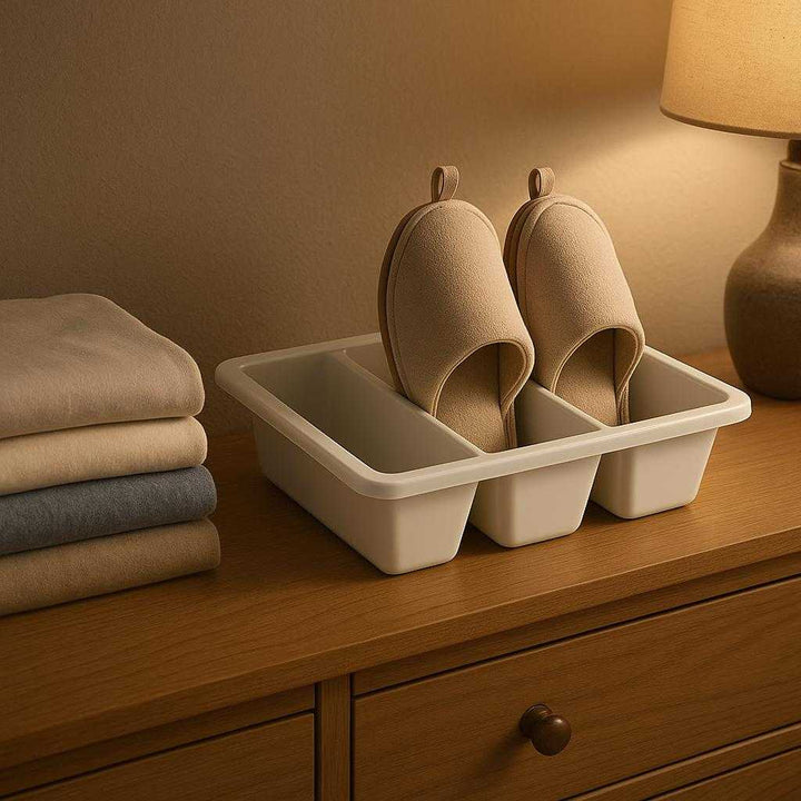 Opbevaring til hjemmesko - Praktisk og pladsbesparende skuffeindsats med flere rum, ideel til garderobeskuffer og hylder: A realistic bedroom setting where the slipper storage drawer insert is properly grounded on a wooden dresser shelf, being naturally placed among neatly folded clothes.