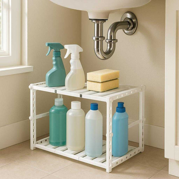Opbevaring under vasken hvid - Professionel pladsudnyttelse og organisering med justerbare hylder: A realistic bathroom setting where the product is properly grounded under a bathroom sink, being actively used to organize cleaning supplies like bottles and sponges.