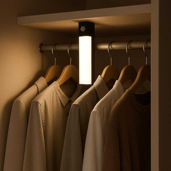 Opladeligt LED-skabslys med bevægelsessensor - Moderne og energieffektiv belysning til hjemmet i sort og lyseblå: A different realistic wardrobe setting where the product is securely positioned inside on a shelf, automatically turning on as the closet door is opened, highlighting the clothes around it with proper physics, shadows, and realistic integration into the environment.