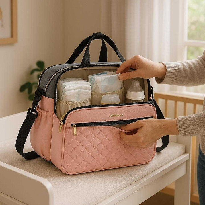 Parent Taske i Polyester med Stor Kapacitet og Flere Rum - Sort, Grå, Lyserød Grå - 38x30x18cm: A realistic nursery room setting where the bag is properly grounded on a changing table, being actively used by a parent who is reaching into the bag for baby supplies.