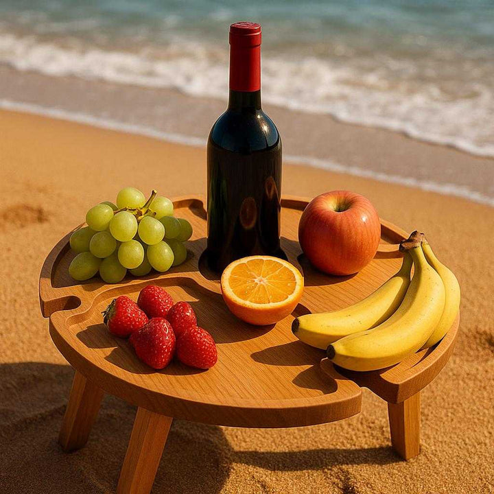 Picnicbakke i rustikt design - Bærbar og kompakt, ideel til udendørs brug. A close-up of the compact picnic basket table on a sandy beach, holding assorted fruits and a bottle of wine, with the ocean waves in the background.