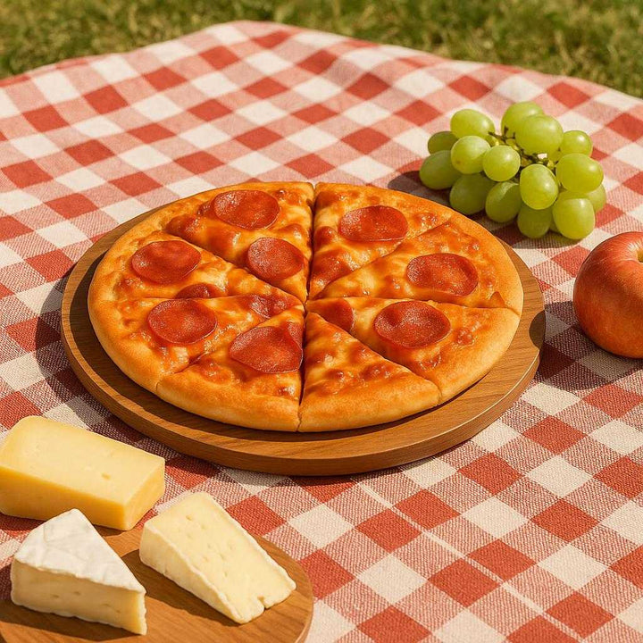Pizza Bræt i Massivt Træ - Let at Bære, Æstetisk, Holdbart - 38.1 cm: A different realistic outdoor picnic setting where the pizza bræt i massivt træ is securely positioned on a checkered picnic blanket, naturally placed with an assortment of cheeses and fruits beside it.